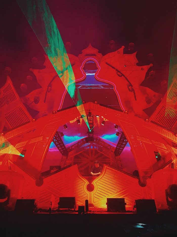 Dynamic laser and light display with a red structure, creating vibrant visual effects at a nighttime event.